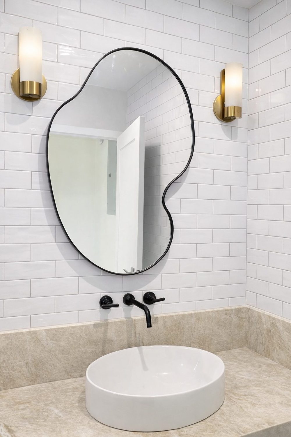 Custom pebble-shape mirror above a stone vanity, subway tile wall