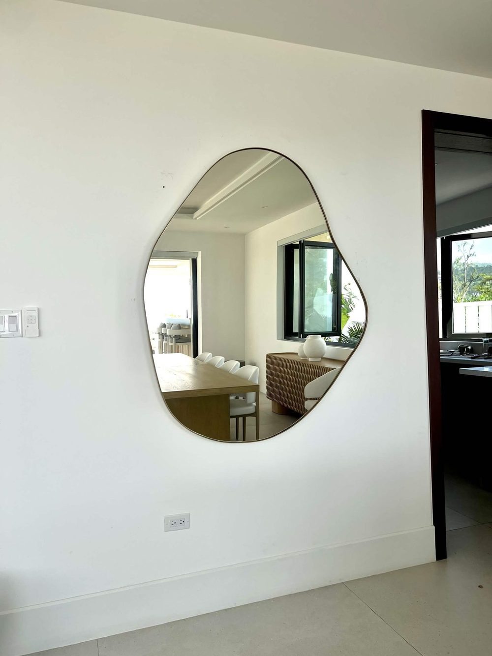 Organic brass-framed mirror in a bright dining room