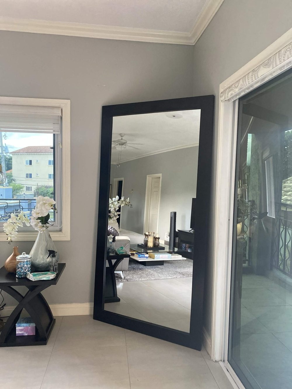 Black-framed floor-standing mirror in a living room
